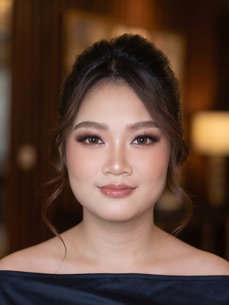 Riasan glam bernuansa hangat dengan mata smokey keemasan, kulit glow, dan bibir glossy